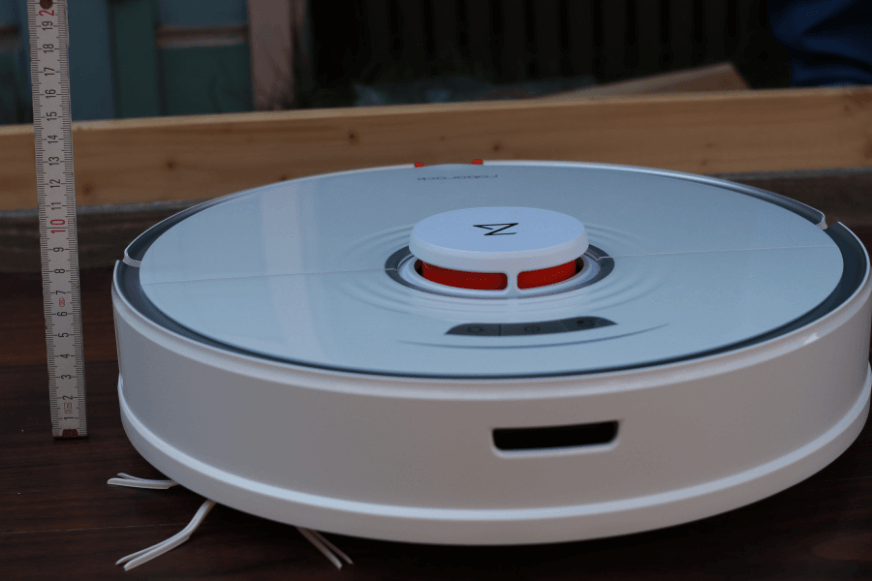 Ein Saugroboter mit einem Lasernavigationsturm wird mit einem Lineal ausgemessen.